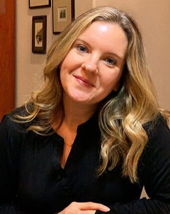 Writer Brooke Walker is pictured in a black blouse while smiling for the camera.